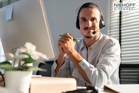 Mann mit Headset am PC Niehoff Sitzmoebel