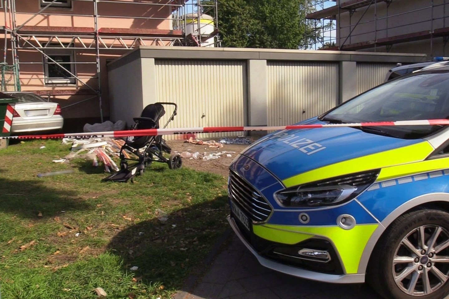 Ein Auto (links hinten) steht an einem Haus, nachdem der Fahrer zuvor eine Frau und ein Kind angefahren und lebensgefährlich verletzt hatte.