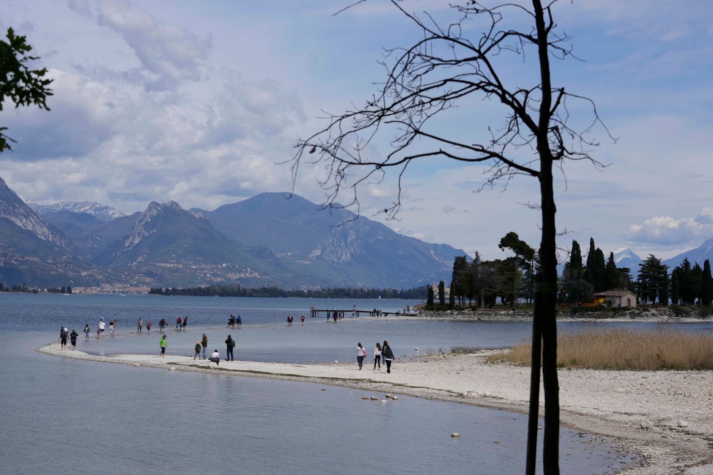 Touristen gehen über einen Streifen Land zwischen dem Festland und der Insel San Biagio.