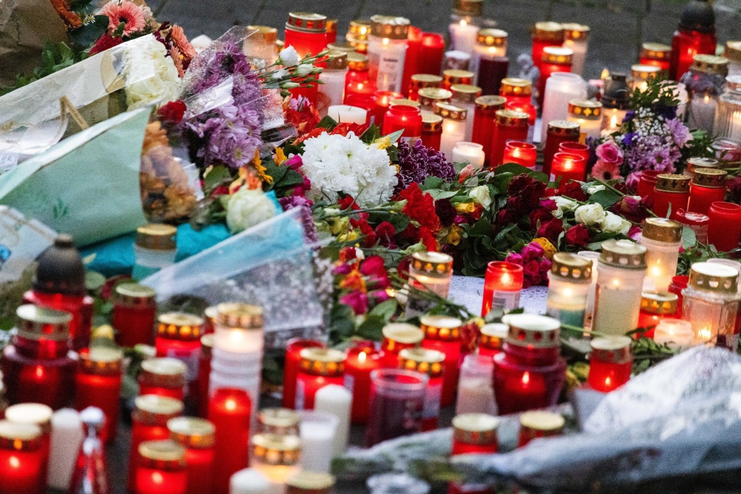 Blumen und Kerzen liegen während einer stillen Gedenkveranstaltung vor der Schule.