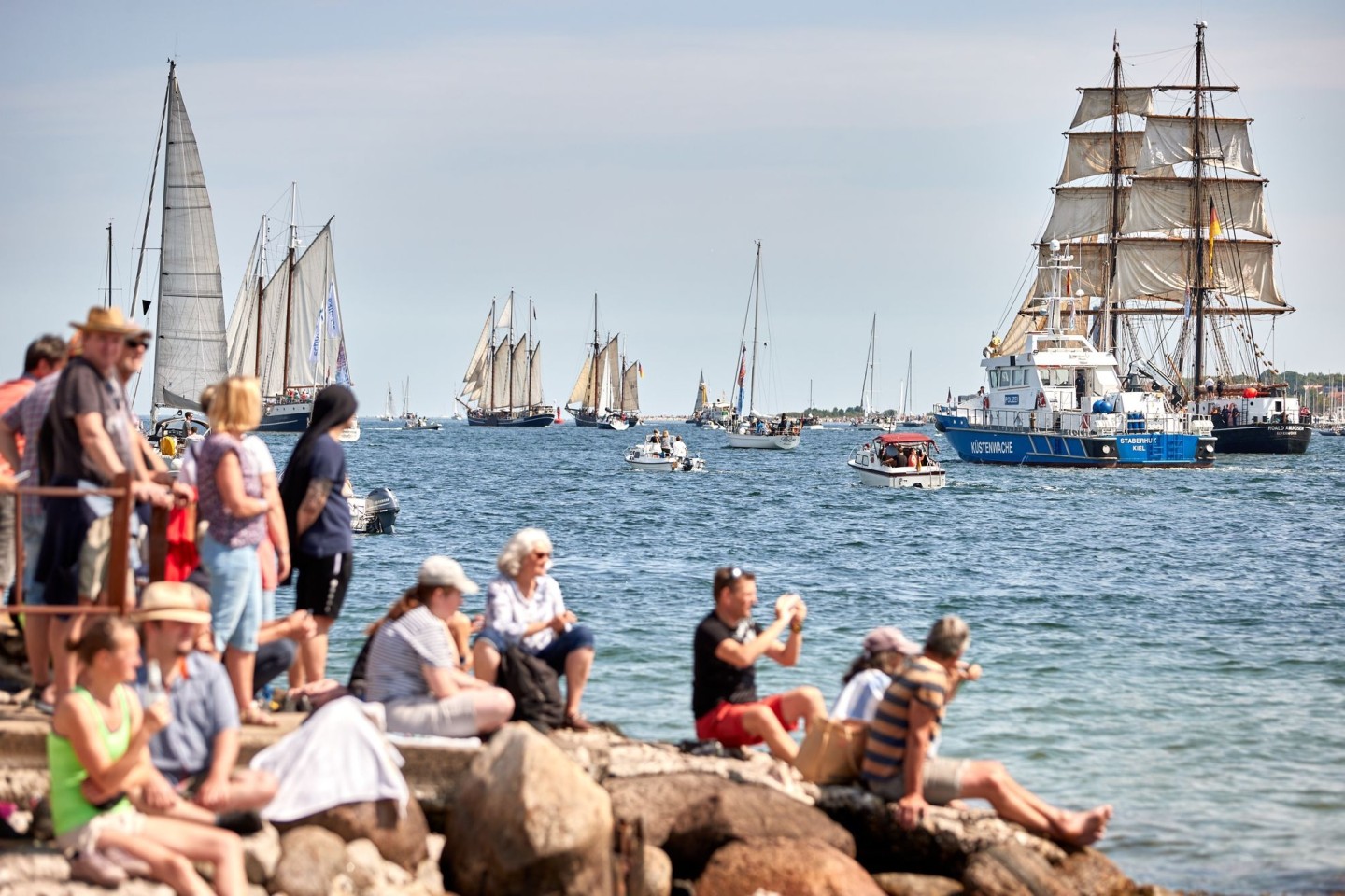 Menschen verfolgen an der Förde die Windjammerparade.