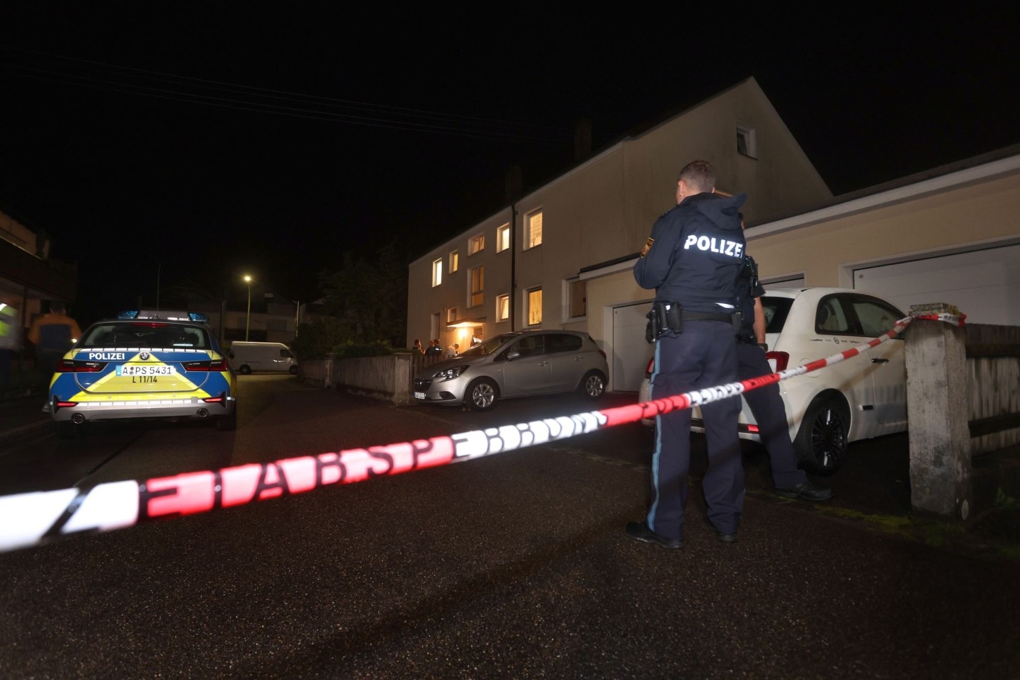 Polizisten stehen vor einem Haus, in dem drei Menschen erschossen wurden.