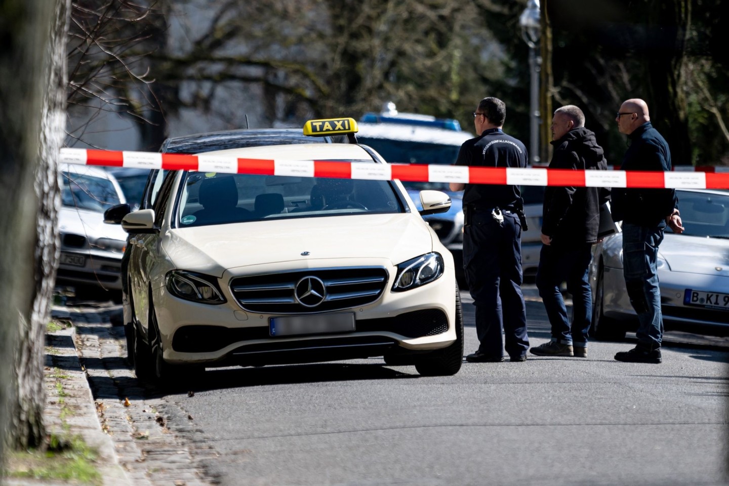 Mitarbeiter der Berliner Polizei stehen vor einem Taxi in Berlin-Grunewald. Am Donnerstagmorgen gab es dort einen tätlichen Angriff auf den Taxifahrer.