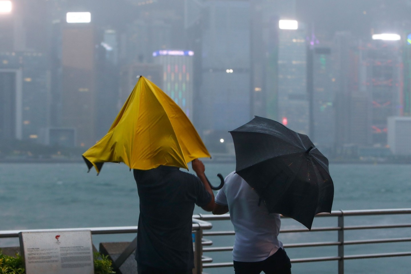 Menschen mit Regenschirmen kämpfen in Hongkong mit starkem Wind und Regen des Taifuns «Saola».