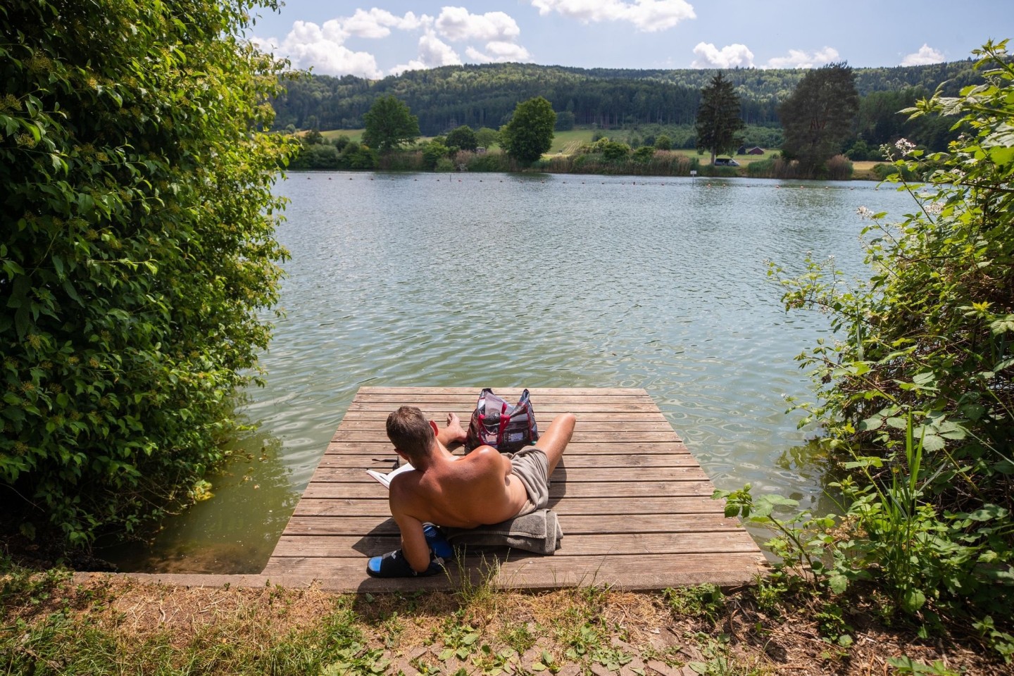 Ein Mann genießt die Sonne am Badesee Plüderhausen - und vielleicht auch den ein oder anderen Sommerhit.